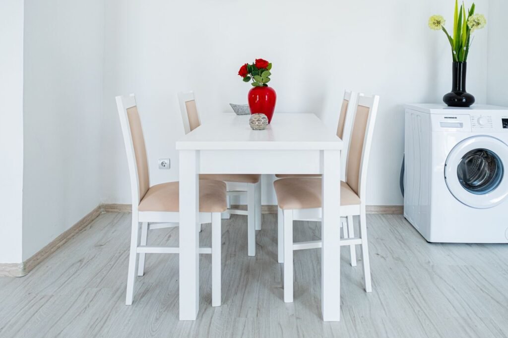 A stylish minimalist dining area with white furniture and red roses.